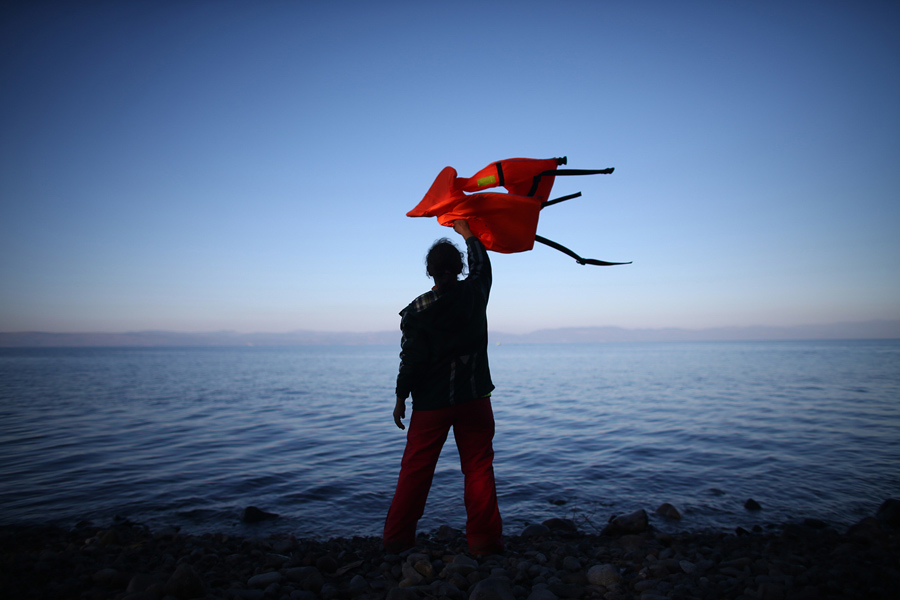 Carl Court / Getty. caption: A woman waves a life jacket to direct a migrant boat ashore as it makes the crossing from Turkey to the Greek island of Lesbos, on November 12, 2015, in Sikaminias, Greece. Rafts and boats continue to make the journey from Turkey to Lesbos each day as thousands flee conflict in Iraq, Syria, Afghanistan, and other countries. Over 500,000 migrants have entered Europe so far this year and approximately four-fifths of those have paid to be smuggled by sea to Greece from Turkey, the main transit route into the EU. Most of those entering Greece on a boat from Turkey are from the war zones of Syria, Iraq, and Afghanistan.