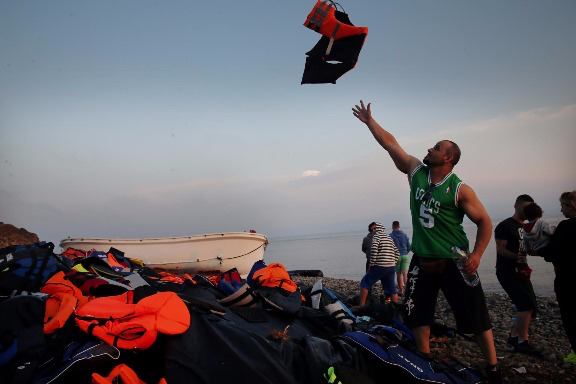 Salal Hassan, 35, from Iraq, tossed his life jacket onto a pile after crossing the Mediterranean Sea. Immediately after landing, the personal trainer changed into his Boston Celtics jersey, a gift from a friend. Craig F. Walker/Globe Staff.