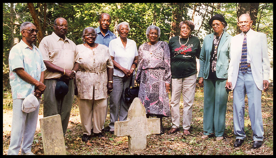Descendants of people interred at Old Orchard Cemetery pose behind the graves of Mat and Julia Palmer. Second from left is Edward Palmer, father of Brian Palmer. Camp Peary–Armed Forces Experimental Training Activity, VA, 1998, Department of Defense photo.