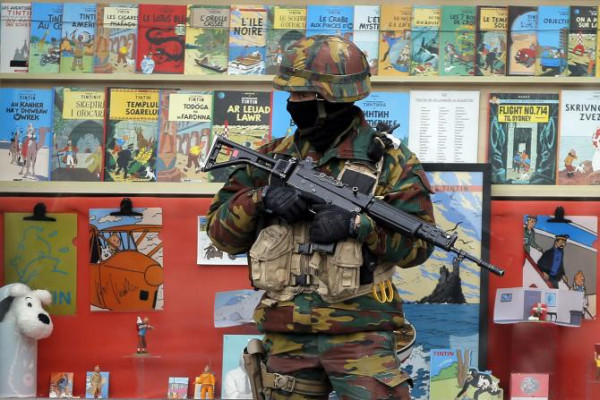 photo 1: Vincent Kessler/Reuters. caption: A Belgian soldier stands guard in front of a shop selling Tintin comic books in central Brussels, March 24, 2016.