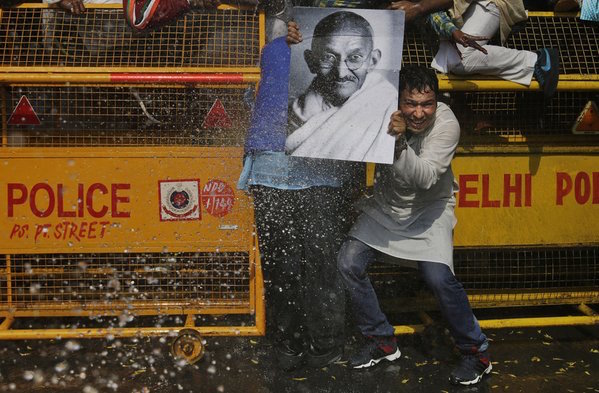 A supporter of the youth wing of India’s opposition Congress Party holds a portrait of the Indian independence leader and renowned pacifist, Mahatma Gandhi, as police use water canons to stop protesters from marching towards Indian Parliament during a protest in New Delhi, India, on March 2, 2016. The protest was against a statement given by Smriti Irani, India’s Human Resource Development Minister, in the Indian Parliament during a debate on recent student protests in the country. Altaf Qadri / AP