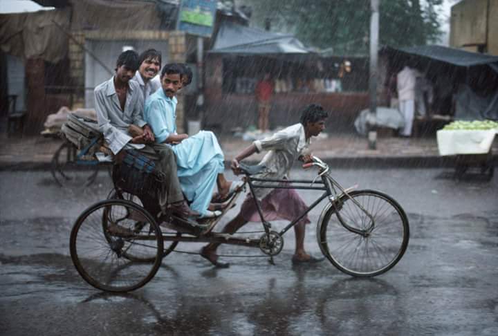 Locals riding a rickshaw through heavy monsoon rain. Steve McCurry unretouched photo. Varanasi, India. 1983