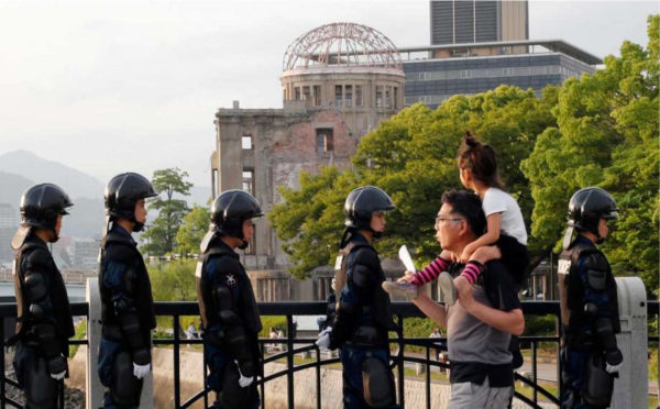 With the Atomic Bomb Dome as a backdrop, passers-by move past riot police near Hiroshima Peace Memorial Museum in Hiroshima, southwestern Japan, Thursday, May 26, 2016. U.S. President Barack Obama is to visit Hiroshima on Friday, May 27 after the Group of Seven summit in central Japan, becoming the first serving American president to do so. Photo: Shuji Kajiyama, AP