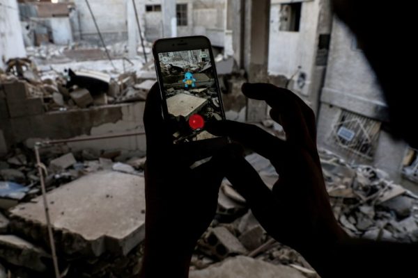 TOPSHOT - A Syrian gamer uses the Pokemon Go application on his mobile to catch a Pokemon amidst the rubble in the besieged rebel-controlled town of Douma, a flashpoint east of the capital Damascus on July 23, 2016. / AFP PHOTO / Sameer Al-Doumy