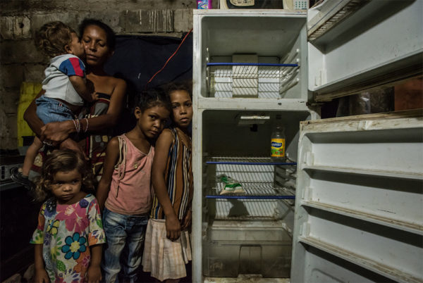 Photo: Meridith Kohut / New York Times. caption: Leidy Cordova, 37, with four of her five children at their home in Cumaná, Venezuela, last week. Their broken refrigerator held the only food in the house: a bag of corn flour and a bottle of vinegar.