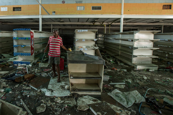 Photo: Meridith Kohut / New York Times. caption: A man searched for food last week at a grocery store in Cumaná that had been looted.