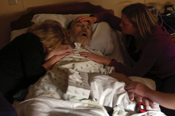 Photo: Lisa Krantz. Caption: As the final moments of his life ticked away, Walt is caressed and comforted. He wasn’t able to die at home, but he was surrounded by his family, which in essence made it “home” for him, Megan said. Walt’s heart -– for decades filled with unbounded love for his wife and kids, patients and friends -– stopped at 3:33 a.m. May 31, 2016.