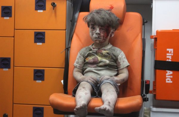 photo: Mahmoud Raslan/Anadolu Agency/Getty Images. caption: A 5-year-old boy, identified in news reports as Omran Daqneesh, sits in an ambulance Wednesday after reportedly being pulled out of a building hit by an airstrike in Aleppo, Syria.