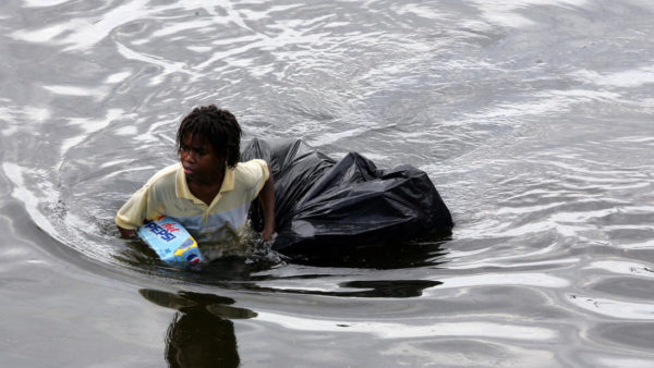 photo: Dave Martin / Associated Press. caption: A young man walks through chest deep flood water after looting a grocery store in New Orleans on Tuesday, Aug. 30, 2005. Flood waters continue to rise in New Orleans after Hurricane Katrina did extensive damage when it made landfall on Monday.