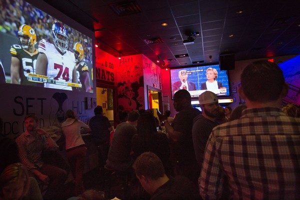 Patrons in a bar watch the second presidential debate between US Democratic presidential candidate Hillary Clinton and US Republican presidential candidate Donald Trump in Washington, DC on October 9, 2016. / AFP / CHRIS KLEPONIS