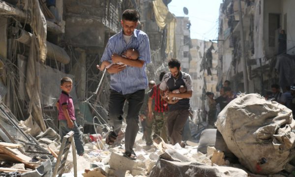 Syrian men carrying babies make their way through a destroyed neighbourhood of Aleppo. Photograph: Ameer Alhalbi/AFP/Getty Images