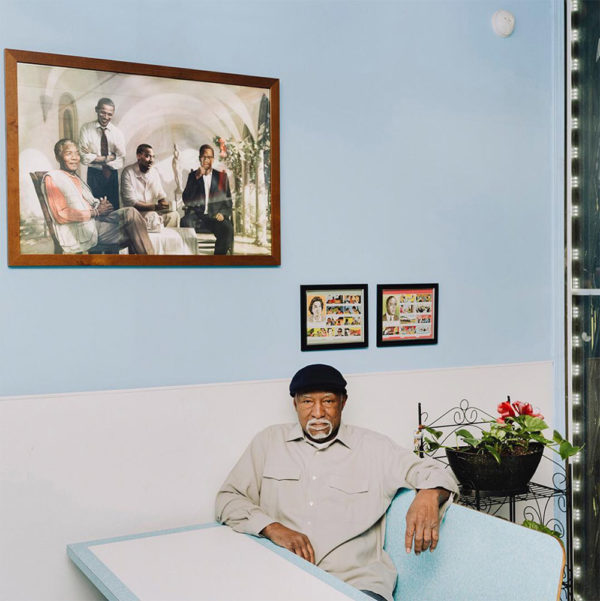 Photo: Whitten Sabbatini for The New York Times. Finnie Haire, the owner of Hairer’s Gulf Shrimp, with a painting featuring Nelson Mandela, the Rev. Dr. Martin Luther King Jr. and Malcolm X, with President Obama standing over them. 