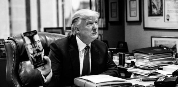 Photo: Robin Groulx / Axios. Caption: Donald Trump, in his office, holds up a copy of "Adams v Jefferson" by John Ferling.