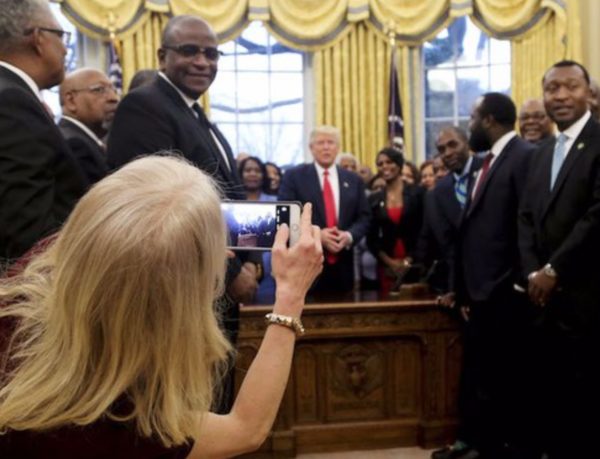 Cropped version of Kellyanne Conway taking a photo as US President Donald Trump and leaders of historically black universities and colleges talk before a group photo in the Oval Office Credit: AFP