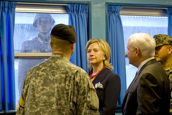 photo: DefenseImagery.mil. U.S. Army Col. Kurt Taylor, left, briefs Secretary of State Hillary Rodham Clinton, center, and Secretary of Defense Robert Gates, right, at the truce village of Panmunjom, in a demilitarized zone (DMZ) north of Seoul, South Korea, July 21, 2010, as a North Korean soldier watches through the window. The DMZ has separated North and South Korea since the Korean War.