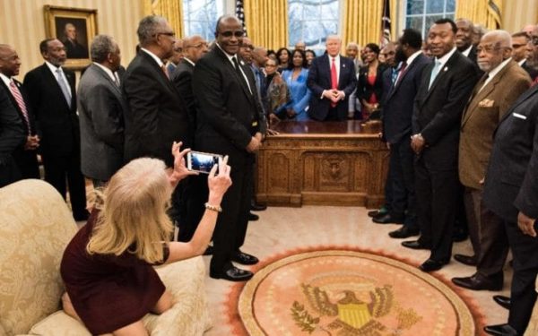 Ms. Conway kneeling on a couch while taking a photo of the group on a cellphone. CreditBrendan Smialowski/Agence France-Presse — Getty Images