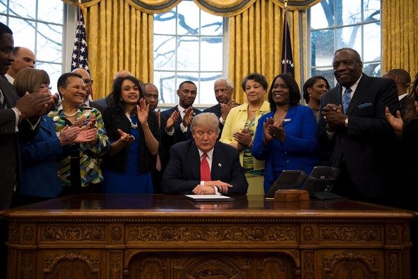 Donald Trump (C) holds up an executive order to bolster historically black colleges and universities (HBCUs) after signing it in the Oval Office of the White House in Washington, DC, February 28, 2017. / AFP / JIM WATSON