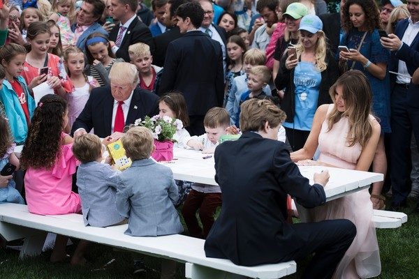 US President Donald Trump, Barron Trump(R) and US First Lady Melania Trump join others to write notes to service members during the Easter Egg Roll on the South Lawn of the White House April 17, 2017 in Washington, DC. / AFP PHOTO / Brendan Smialowski