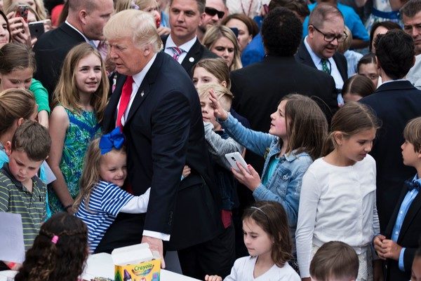 US President Donald Trump receives a hug during the Easter Egg Roll on the South Lawn of the White House April 17, 2017 in Washington, DC. / AFP PHOTO / Brendan Smialowski