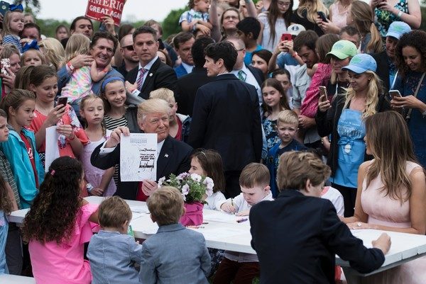 US President Donald Trump, Barron Trump(R) and US First Lady Melania Trump join others to write notes to service members during the Easter Egg Roll on the South Lawn of the White House April 17, 2017 in Washington, DC. / AFP PHOTO / Brendan Smialowski