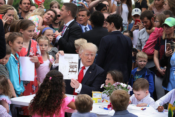 U.S. President Donald Trump (C) holds up the coloring sheet he wrote on while joining children at a craft table during the 139th Easter Egg Roll on the South Lawn of the White House April 17, 2017 in Washington, DC. The White House said 21,000 people are expected to attend the annual tradition of rolling colored eggs down the White House lawn that was started by President Rutherford B. Hayes in 1878. (April 16, 2017 - Source: Chip Somodevilla/Getty Images