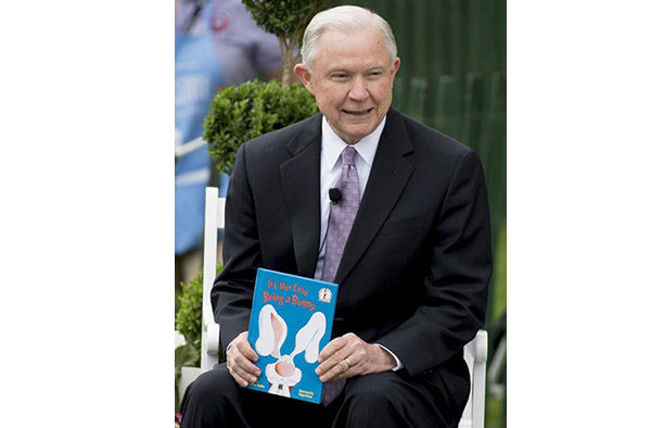 Attorney General Jeff Sessions reads a book during the 139th White House Easter Egg Roll on the South Lawn of the White House in Washington, DC, April 17, 2017. / AFP PHOTO / SAUL LOEB