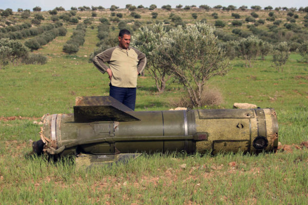 A Syrian man stands next to an unexploded ground-to-ground missile, fired by government forces on the southern Syrian city of Daraa on March 27, 2017. Photo: Mohamad Abazeed / AFP / Getty
