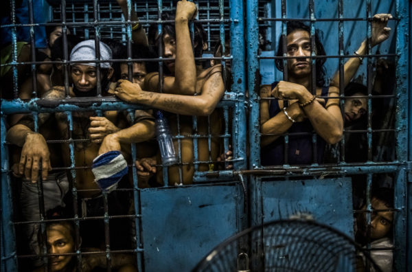 Photo: Daniel Berehulak Caption: Inmates at a Manila police station watched as more drug suspects were processed after their arrests.