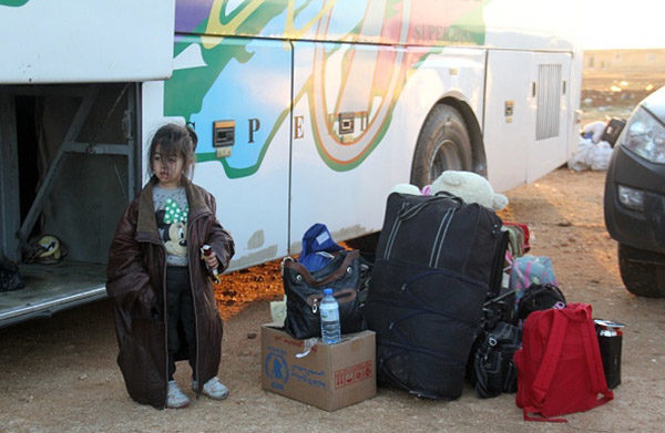 A Syrian child who was a part of a convoy of opposition fighters and their families, evacuated from the Waer neighbourhood, the last opposition-held district in the central city of Homs, stands next to a bus after their arrival in the Maaret al-Ikhwaan village north of Idlib, on May 22, 2017. The Syrian regime on May 21 regained total control of the central city of Homs with the evacuation of rebels from the last area they had controlled. Photo: OMAR HAJ KADOUR/AFP/Getty Images