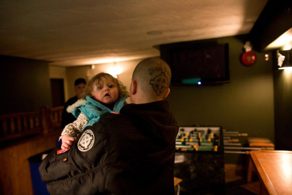 Conor carries another skinhead’s daughter. The young girl’s parents were both members of the Neo-Nazi group. Photo: Brett Gundlock