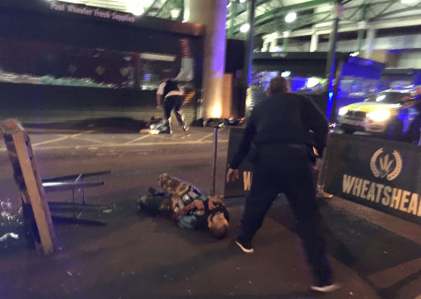 Armed police stand over what is believed to be a suspect shot at the scene of a terror attack outside Borough Market in central London on June 3, 2017. A van ploughed into pedestrians and several people were stabbed in London on Saturday, leaving at least 20 casualties in what police called a "terrorist" attack days before a general election. Armed police opened fire during two "terrorist incidents" at London Bridge and nearby Borough Market, a popular nightspot teeming with bars. / AFP PHOTO / Gabriele SCIOTTO