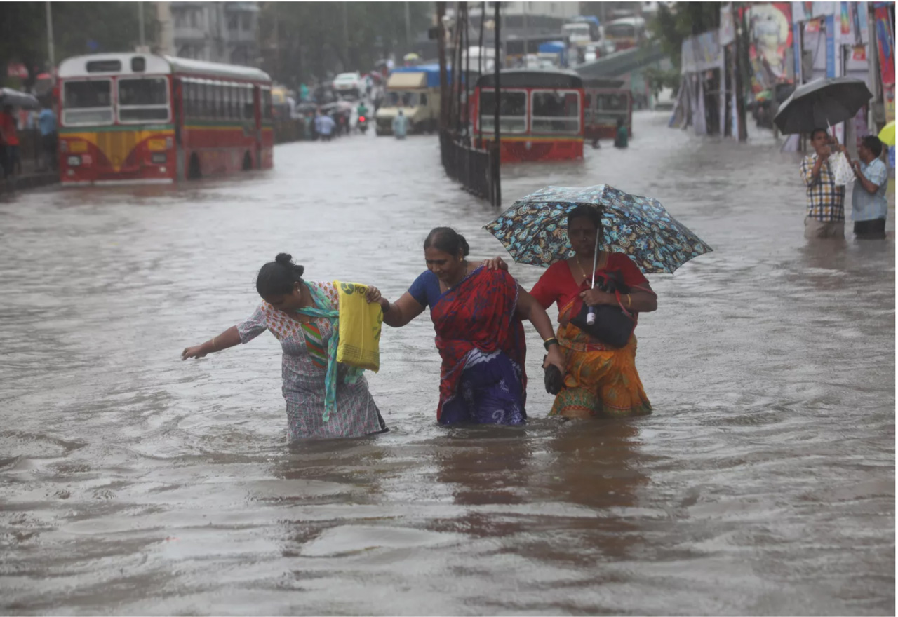 Photo: Imtiyaz Shaikh /Anadolu Agency/Getty Images. Caption: Indians wade along a flooded street during heavy rain in Mumbai, India on August 29, 2017.