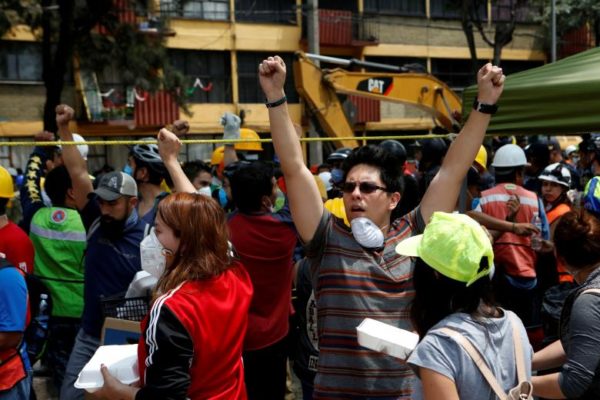 People motion to others to be quiet as rescue workers are searching for survivors under the rubble of a collapsed building in Mexico City. REUTERS/Ginnette Riquelme