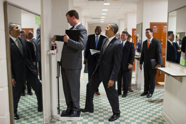Photo: Pete Souza Caption: Aug. 8, 2010 "We were walking through a locker room at the University of Texas when White House trip director stopped to weigh himself on a scale. Unbeknownst to him, the President was stepping on the back of the scale, as Marvin continued to slide the scale lever. Everyone but Marvin was in on the joke." (Official White House Photo by Pete Souza)<br /> steps on a scale that Trip Director Marvin Nicholson is weighing himself on, during a hold in the volleyball locker room at the University of Texas in Austin, Texas, Aug. 9, 2010. Personal Aide Reggie Love, Assistant Press Secretary Bill Burton, and Victor "Vic" Erevia, United States Secret Service laugh in the background.