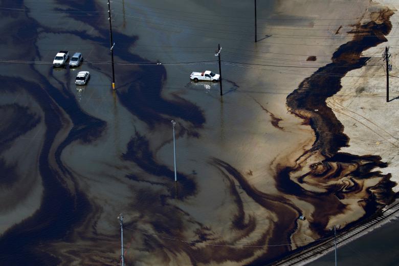 Vehicles sit amid leaked fuel mixed in with floodwaters in the parking lot of Motiva Enterprises LLC in Port Arthur. REUTERS/Adrees Latif
