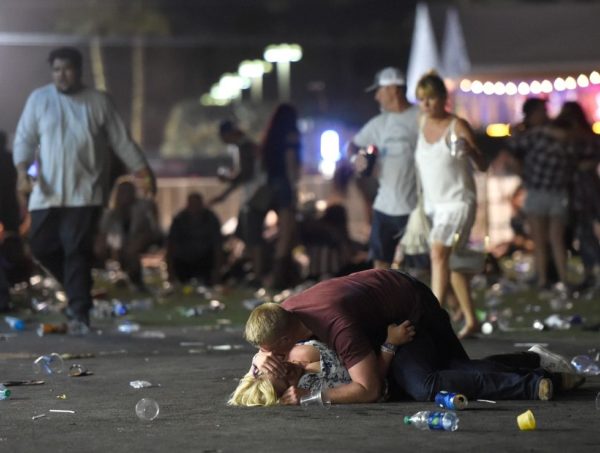 A man lays on top of a woman as others flee the Route 91 Harvest country music festival grounds after a active shooter was reported on October 1, 2017 in Las Vegas, Nevada.