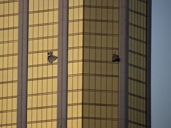 Drapes billow out of broken windows at the Mandalay Bay resort and casino Monday, Oct. 2, 2017, on the Las Vegas Strip following a deadly shooting at a music festival in Las Vegas. A gunman was found dead inside a hotel room. (AP Photo/John Locher)