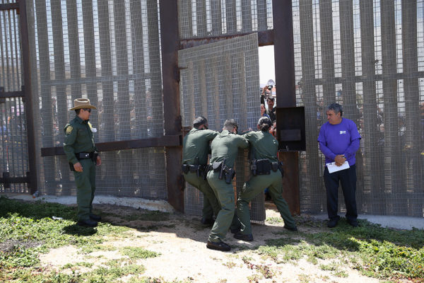 SAN DIEGO, CA - APRIL 30: U.S. Border Patrol agents open a door in the U.S.-Mexico Border fence during an "Opening the Door of Hope" event on April 30, 2016 in San Diego, California. Five families, with some members living in Mexico and others in the United States, were permitted to meet and embrace for three minutes each at a door in the fence, which the U.S. Border Patrol opened to celebrate Mexican Children's Day. It was only the third time the fence, which separates San Diego from Tijuana, had been opened for families to briefly reunite. The event was planned by the immigrant advocacy group Border Angels. (Photo by John Moore/Getty Images)