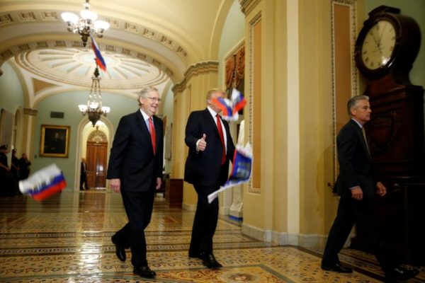 President Trump gestures to reporters as Russian flags thrown from a protester fall in front of him and Senate Majority Leader Mitch McConnell as they arrive for the Republican policy luncheon on Capitol Hill. REUTERS/Joshua Roberts