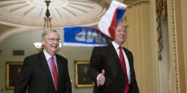 President Trump gestures to reporters as Russian flags thrown from a protester fall in front of him and Senate Majority Leader Mitch McConnell as they arrive for the Republican policy luncheon on Capitol Hill. Photo: J. Scott Applewhite/AP