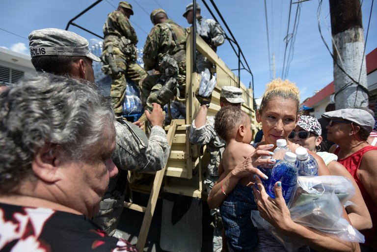 Photo 3: Calos Giusti / Associated Press. Caption: Members of the National Guard distribute water and food after Hurricane Maria in Puerto Rico.