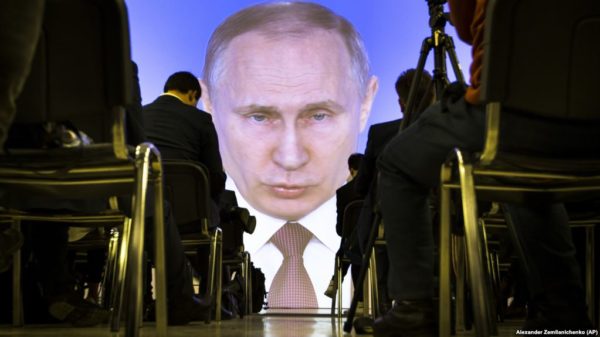 Journalists watch as Russian President Vladimir Putin gives his annual state of the nation address in Manezh in Moscow, Russia, Thursday, March 1, 2018. Putin set a slew of ambitious economic goals, vowing to boost living standards, improve health care and education and build modern infrastructure in a state-of-the-nation address. (AP Photo/Alexander Zemlianichenko)