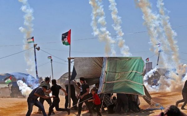 Palestinians run for cover from tear gas near the border between Israel and the Gaza Strip, east of Jabaliya on May 14, 2018 (AFP PHOTO / Mohammed ABED)