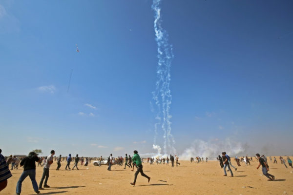 Palestinian protesters run during clashes with Israeli forces near the Gaza border on May 15, 2018