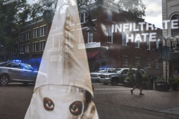 Photo: Michael Robinson Chavez/The Washington Post. Aug. 11, 2018 In downtown Charlottesville, state police vehicles are reflected in a window display advertising Spike Lee's new film “BlacKkKlansman.”