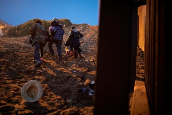 Migrants from Honduras walk towards U.S. Customs and Border Protection officials (not pictured) in San Diego County, after crossing illegally from Mexico to the U.S. by jumping a border fence, photographed through the border wall in Tijuana, Mexico, December 2, 2018. REUTERS/Alkis Konstantinidis