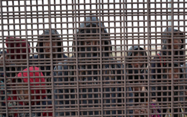 Photo: John Moore/getty Images Central American immigrants wait at a “double mesh” border fence after crossing the Rio Grande from Mexico to El Paso, Texas. They said they had crossed the river the evening before and waited by the fence overnight, with temperatures at about 40F degrees. After arriving to American soil, the families are taken into custody by US Border Patrol agents to then request political asylum. Because the river there is shallow, many wade across it instead of entering Texas via an official port of entry, where they may have to wait weeks, or months to receive an asylum interview. US border officials limit the number of migrants that can pass through ports of entry on a daily basis, a process called “metering.”