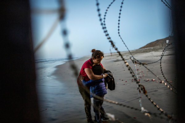 Photo: Fabio Bucciarelli for Yahoo News. A Central America migrant woman hugs her child at San Diego's beach, after crossing the Mexico-US border wall at Tijuana Beach, Mexico, December 14, 2018.