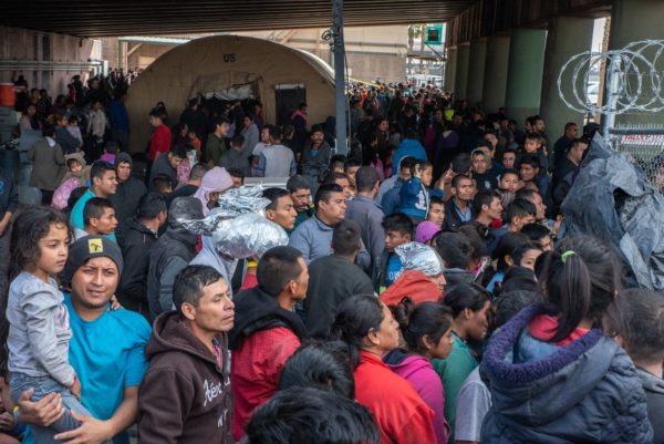 Migrants gather inside the fence of a makeshift detention center Wednesday in El Paso, where a surge has been overwhelming Border Patrol and the U.S. immigration infrastructure. (Sergio Flores for The Washington Post)