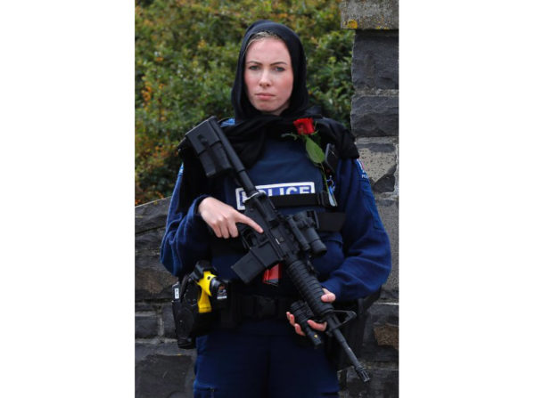 A police officer stands guard with a rose to pay respect at the service for a victim of the Friday March 15 mosque shootings for a burial at the Memorial Park Cemetery in Christchurch, New Zealand, Thursday, March 21, 2019. (AP Photo/Vincent Yu)